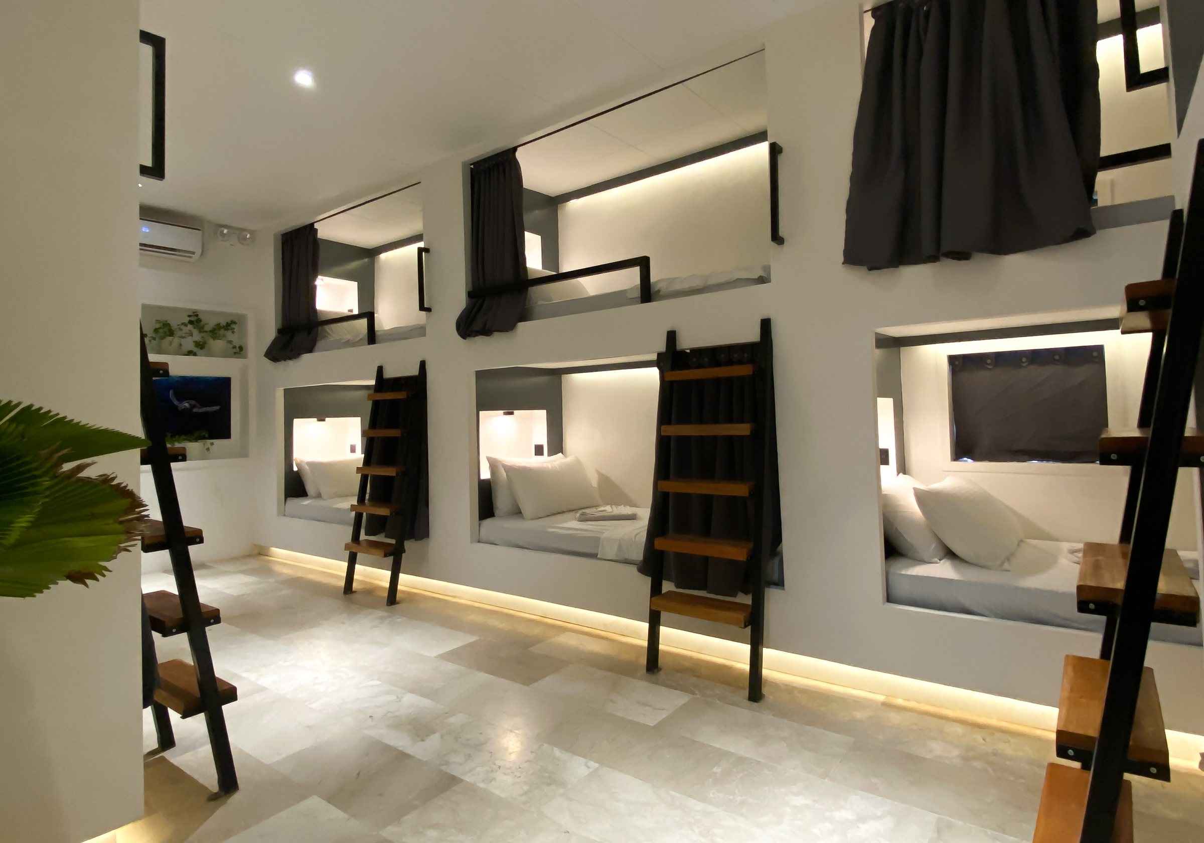 10-bed dorm with lit bunks and privacy curtains